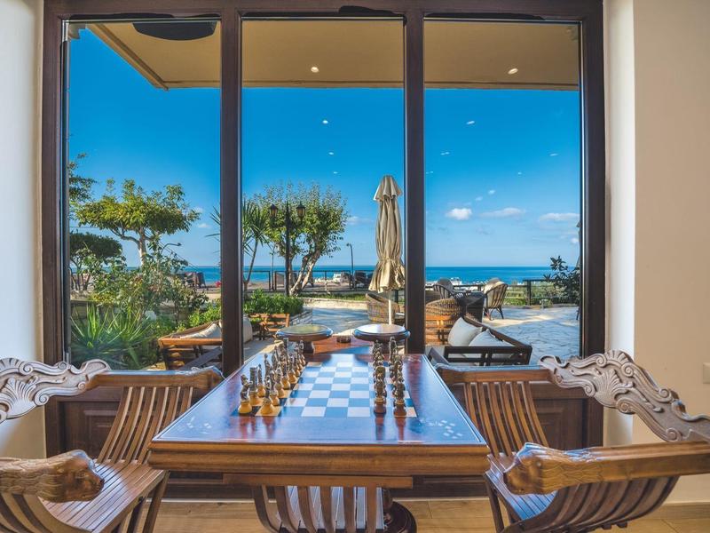 Essbereich mit Holz­tisch und Stühlen mit Blick auf Terrasse und Meer.