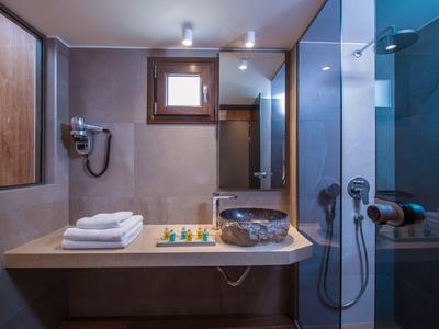 Modernes Badezimmer mit Waschtisch, Handtüchern, Seifenspendern, Föhn und Glasdusche.