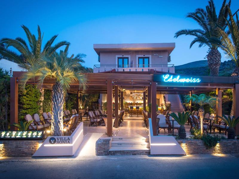 Moderne hotelbar met palmbomen en uitnodigende verlichting 's nachts.