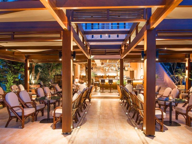 Verlichte buitenterras met houten structuur, stoelen en planten bij schemering.