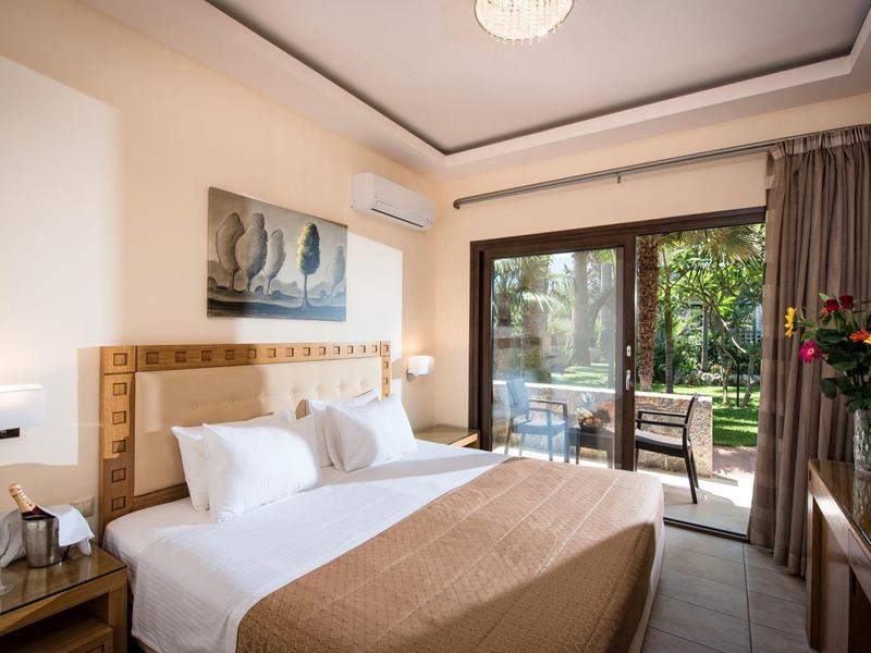 Licht en ruim hotelkamer met tweepersoonsbed en uitzicht op tuin en terras.