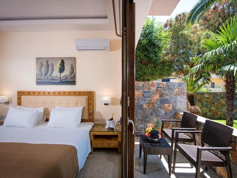 Gezellige tweepersoonskamer met balkon en uitzicht op een groene tuin met palmbomen.