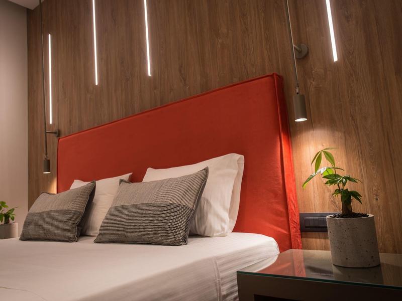 Moderne slaapkamer met rood gevoerd hoofdeinde en zachte verlichting.