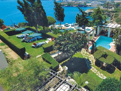 Vista su un giardino con sedie a sdraio, piscina e vista sul mare con colline circostanti.