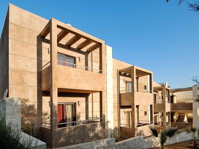 Edifici moderni beige con balconi sotto un cielo azzurro limpido.