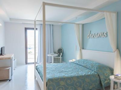 Světle zařízená ložnice s postelí s nebesy, modrou zdí a koupelnou v pozadí.