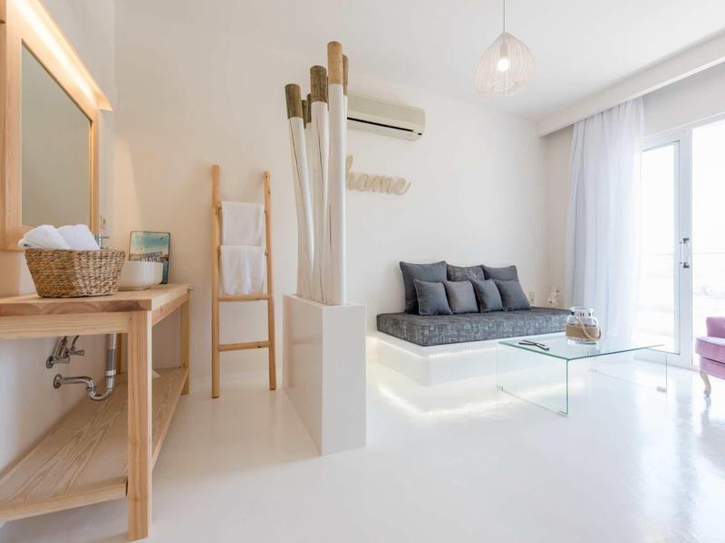 Moderně zařízený obývací pokoj se šedou pohovkou, skleněným stolkem a světlými zdmi