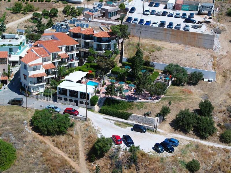 Letecký pohled na malý hotel s parkovištěm a okolní suchou krajinou.