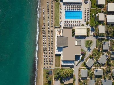 Widok z lotu ptaka na plażę z hotelem, basenami i leżakami przy morzu.