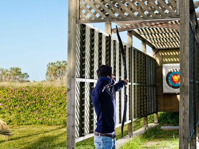 Osoba ćwicząca strzelanie z łuku pod drewnianą kratownicą na świeżym powietrzu