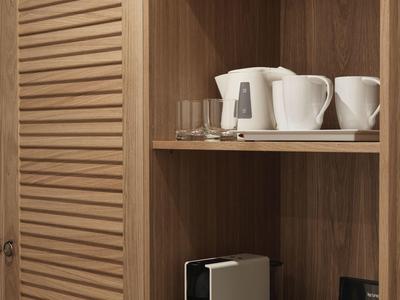 Drewniana półka z czajnikiem, filiżankami i akcesoriami do kawy w pokoju hotelowym