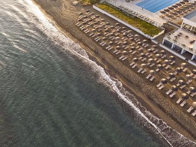 Pláž s deštníky a lehátky u hotelu u moře při západu slunce.
