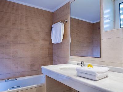 Jasna łazienka z dużym lustrem na ścianie, wanną i złożonymi ręcznikami na blacie.