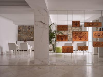 Moderner Hotel-Loungebereich mit weißen Stühlen und einer künstlerischen hängenden Dekoration aus Holzpaneelen.