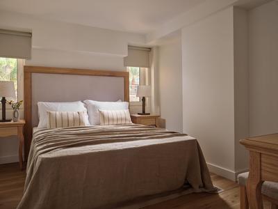 Schlafzimmer mit Doppelbett, beigen Bettdecken und Holzmöbeln in einem hellen Raum.