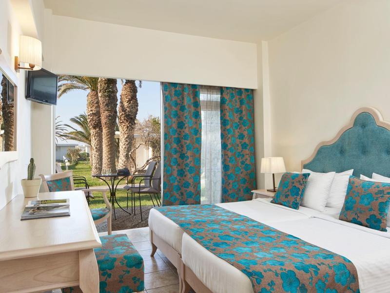 Jasny pokój hotelowy z podwójnym łóżkiem, widokiem na ogród i palmy