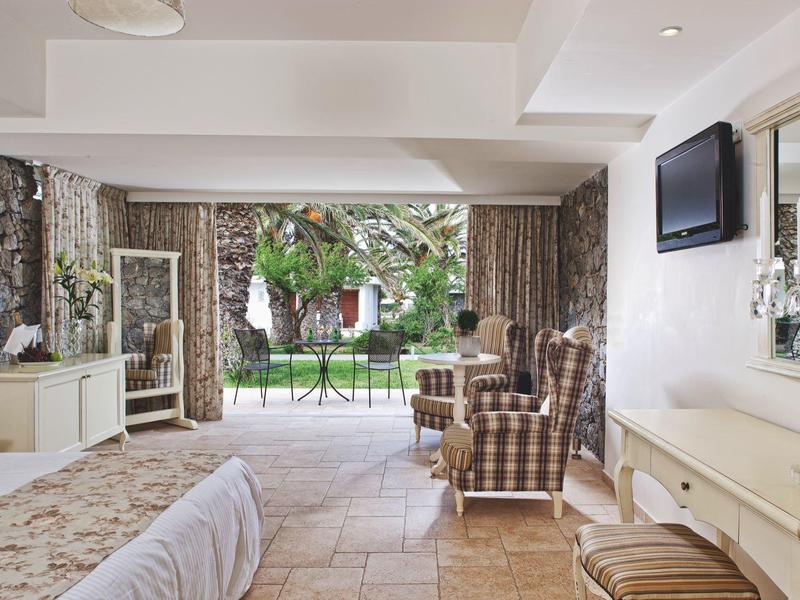 Przytulny salon z fotelami, telewizorem i widokiem na taras w ogrodzie.