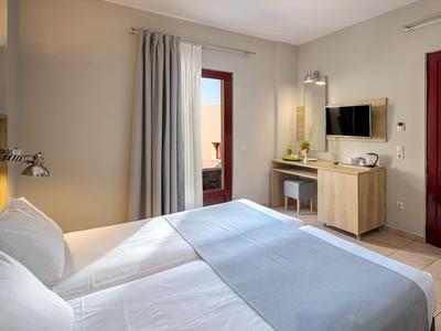 Habitación de hotel acogedora con cama doble, escritorio, TV y acceso a balcón o terraza.