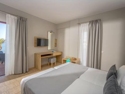 Habitación de hotel moderna con cama doble, escritorio, televisor y balcón con vistas al mar.