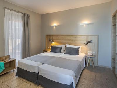 Habitación de hotel moderna con dos camas, mesitas y lámparas de pared elegantes.