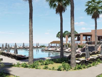 Área de piscina de lujo con palmeras, tumbonas y sombrillas junto a edificios del hotel.