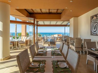 Modernes Restaurant mit Blick aufs Meer, hellem Interieur und gedeckten Tischen.