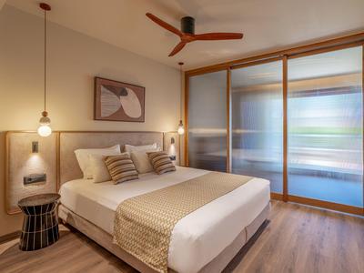 Gemütliches Hotelzimmer mit großem Bett, modernen Lampen und Holzdeckenventilator.