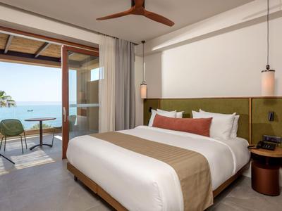 Modernes Hotelzimmer mit Doppelbett und Meerblick vom Balkon.