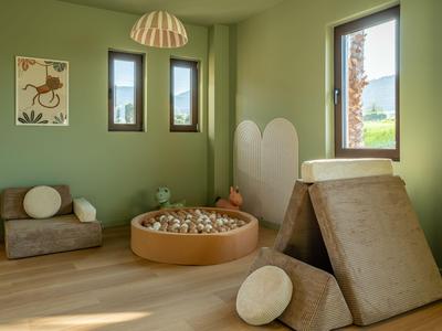 Modern eingerichteter Raum mit grünen Wänden, Holzspielzeug und Sitzpolstern.