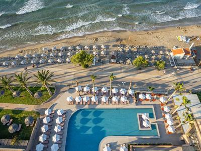 Blick von oben auf Hotelpool, Sonnenschirme, Strand und das Meer im Hintergrund.