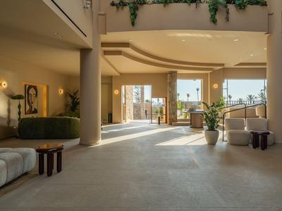 Heller, moderner Hotel-Lobbybereich mit großen Fenstern und bequemen Sitzbereichen.