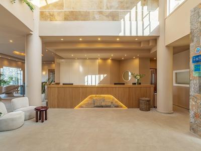 Helle Hotellobby mit Empfangstresen, Sitzgelegenheiten und moderner Beleuchtung.