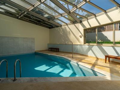 Helles Innenhallenbad mit Holzbank und großen Fenstern für Tageslicht.
