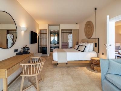 Helles Hotelzimmer mit Doppelbett, Schreibtisch, spiegel und Sitzbereich in modernen Tönen.