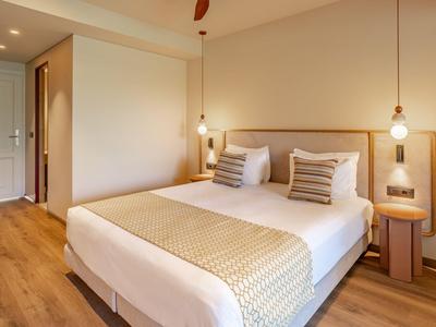 Modern eingerichtetes Hotelzimmer mit Doppelbett, Holzboden und warmen Beleuchtungselementen.