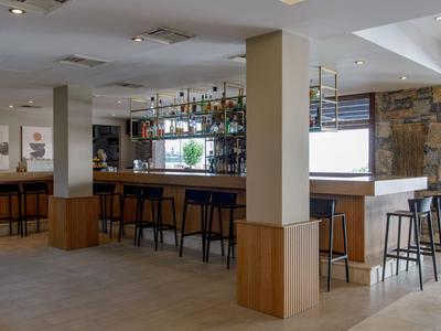 Moderner Hotelbarbereich mit hohen Stühlen und hellem Holzdesign.