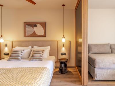 Modernes Hotelzimmer mit Doppelbett, Sitzbereich und minimalistischer Dekoration in warmen Tönen.