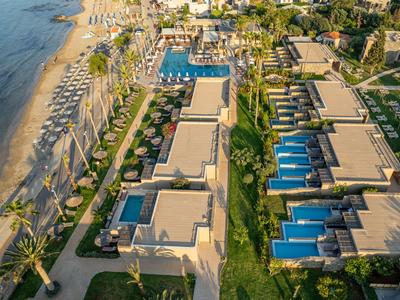 Luftaufnahme eines luxuriösen Resorts am Strand mit Pools und vielen Sonnenschirmen.