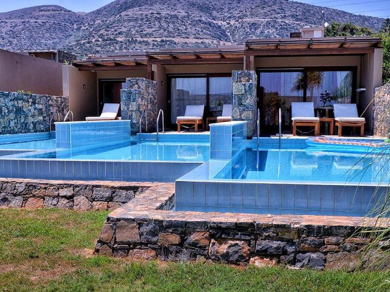 Complexe de luxe avec piscines en terrasses devant un paysage montagneux.