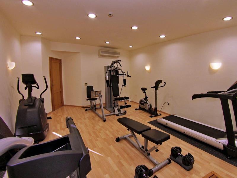 Petite salle de sport avec vélos d'exercice, machines de musculation et tapis roulant sur sol en bois.