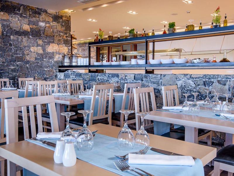 Restaurant d'hôtel moderne avec chaises en bois, tables bien dressées et murs en pierre.