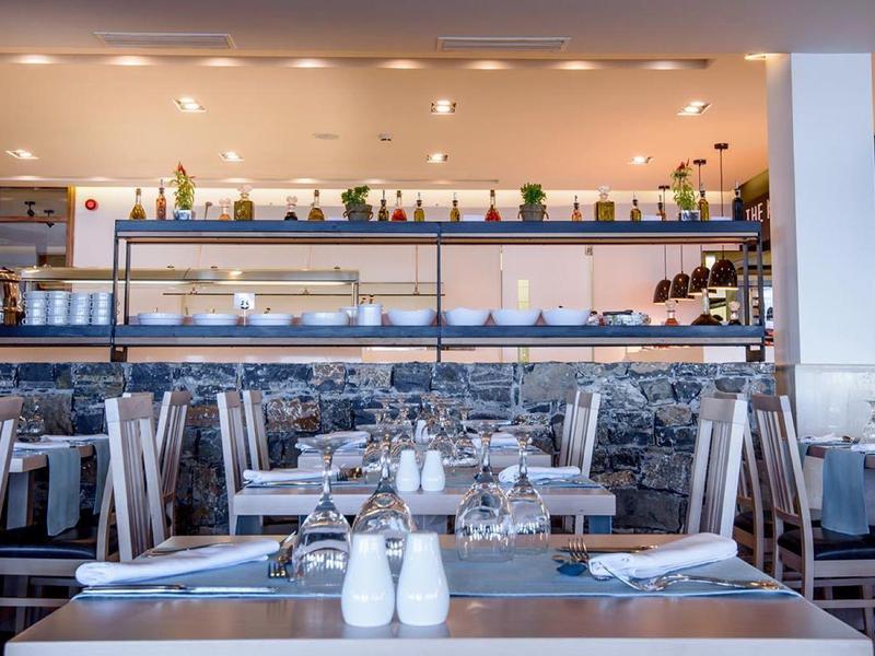 Restaurant moderne avec des tables bien rangées et des étagères remplies de verres et bouteilles.