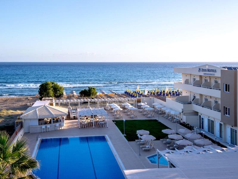 Hôtel avec piscine et transats donnant sur la plage et l'océan.