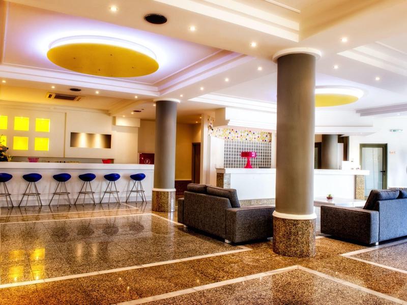 Hall d'hôtel moderne avec tabourets de bar, canapés et éclairage au plafond.