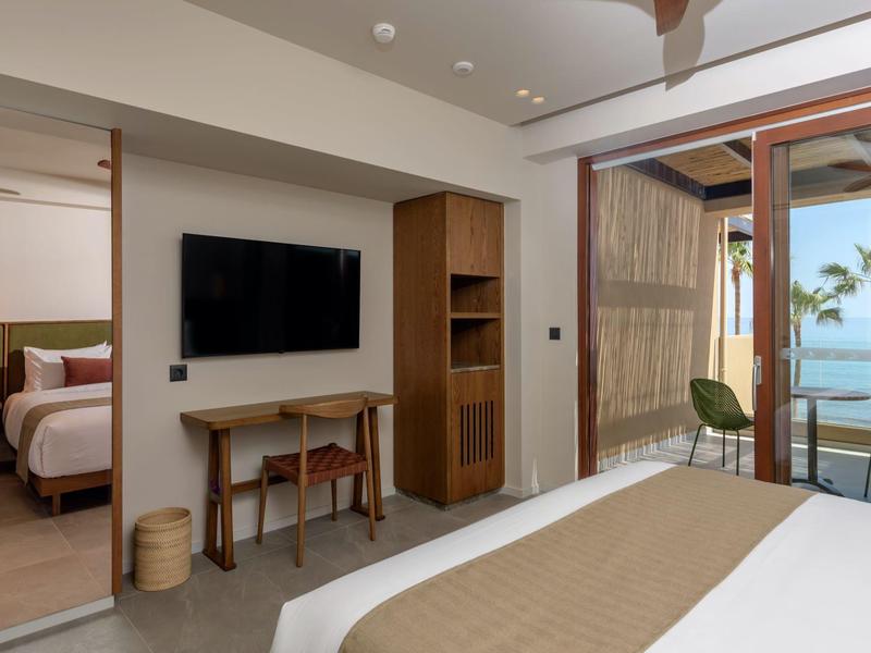 Chambre d'hôtel moderne avec TV, bureau et balcon avec vue sur la mer et les palmiers