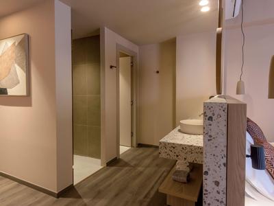 Couloir d'hôtel moderne avec murs clairs, sol en bois et œuvre d'art au mur.