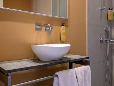 Aménagement de salle de bains moderne avec lavabo ovale posé sur un comptoir en pierre grise.