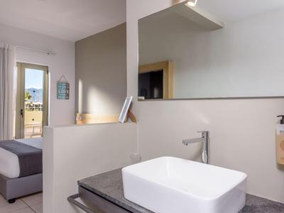 Chambre d'hôtel lumineuse avec lavabo moderne et vue sur la chambre avec balcon.