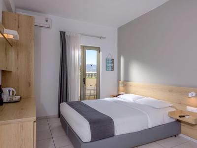 Chambre d'hôtel moderne avec lit double, mobilier en bois et vue sur balcon.