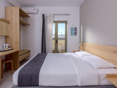 Chambre d'hôtel moderne avec grand lit, meubles en bois et balcon avec vue sur la montagne.